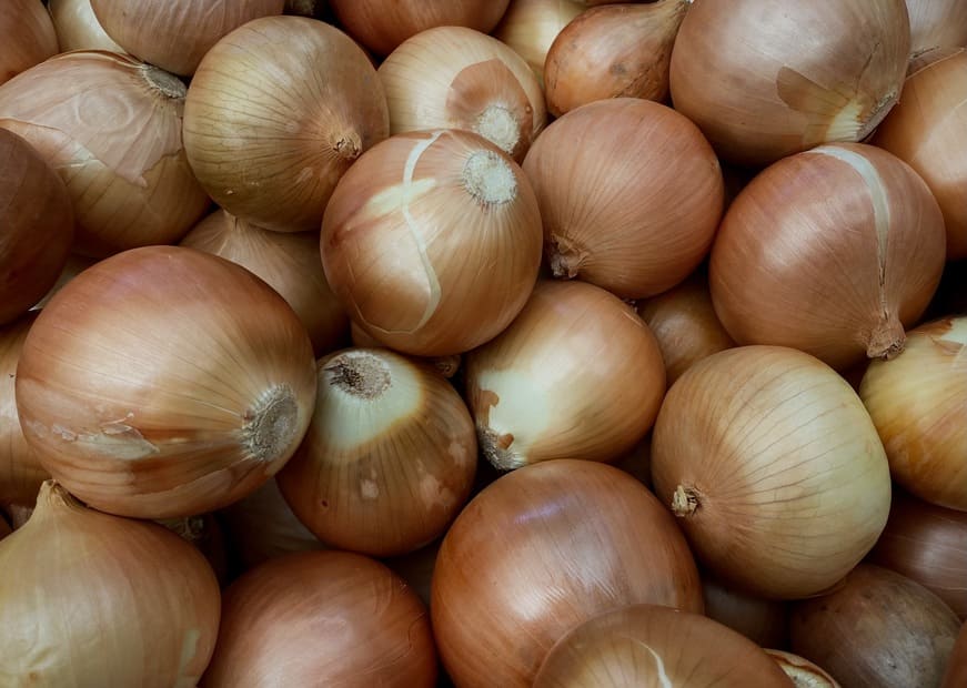 Un montón de cebollas marrones apiladas juntas.